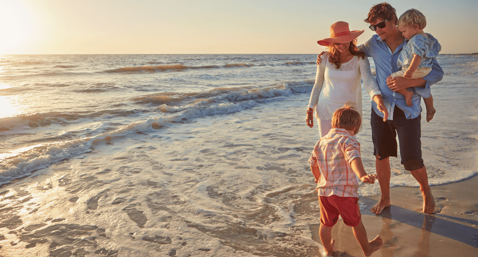 Family walking on a beach at sunset